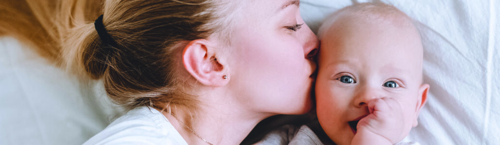 mom kissing newborn baby